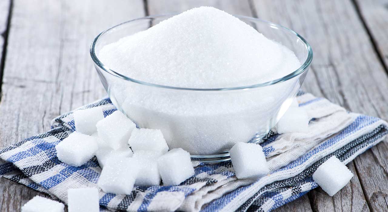 a bowl of sugar surrounded by cubes of sugar