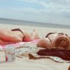 two women sunbathing on towels at the beach