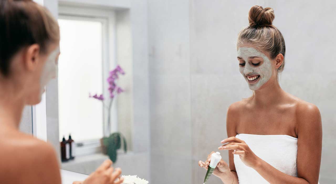 woman in a bathroom applying a face mask