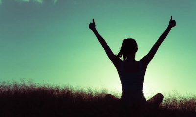 woman sitting on a hill giving two thumbs up