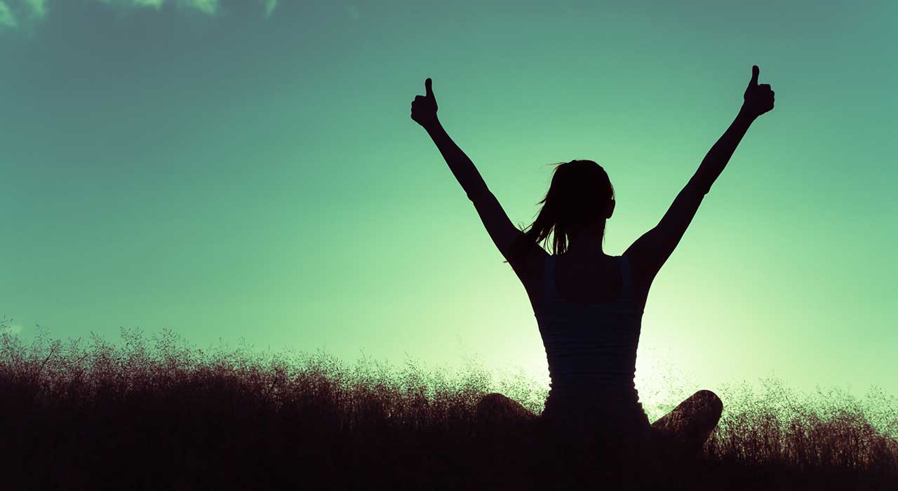 woman sitting on a hill giving two thumbs up