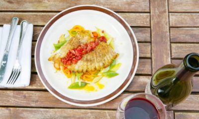 a plate of food on a wooden table with a bottle of wine and a glass