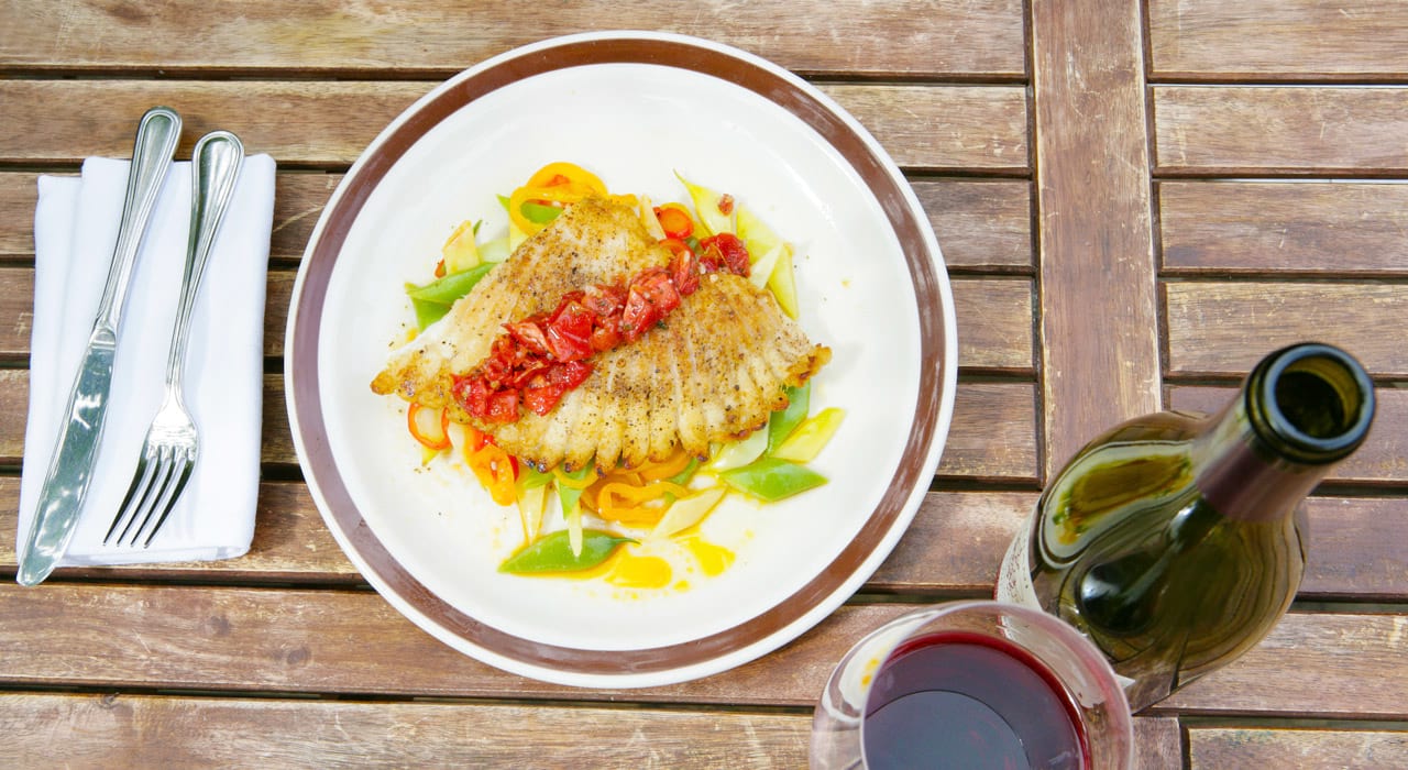 a plate of food on a wooden table with a bottle of wine and a glass