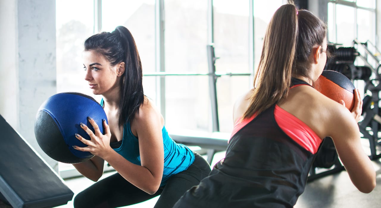 two fit women performing abs exercises in a gym studio