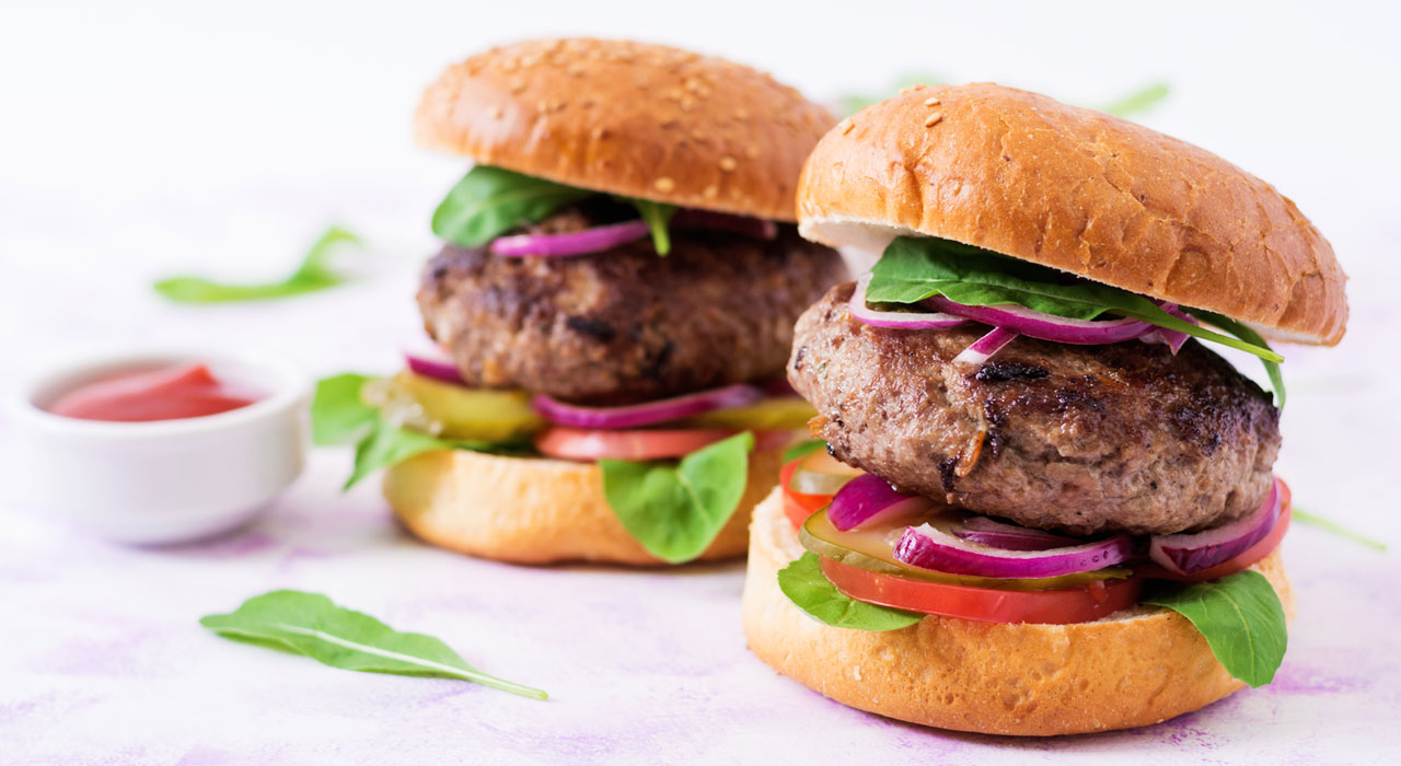 two burgers side by side next to a pot of sauce