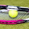 two tennis rackets and a tennis ball on some grass