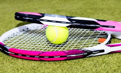 two tennis rackets and a tennis ball on some grass