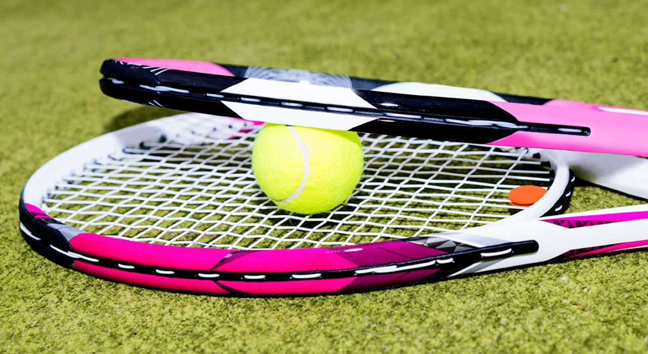 two tennis rackets and a tennis ball on some grass