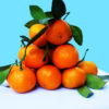 a pile of oranges on a table corner with a light blue background