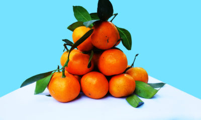a pile of oranges on a table corner with a light blue background