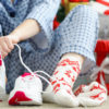 woman in pyjamas putting on running shoes next to presents