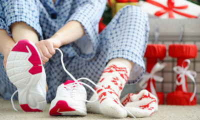 woman in pyjamas putting on running shoes next to presents