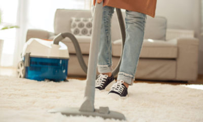 a woman hoovering her living room carpet