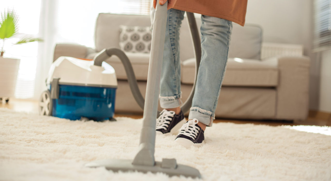 a woman hoovering her living room carpet