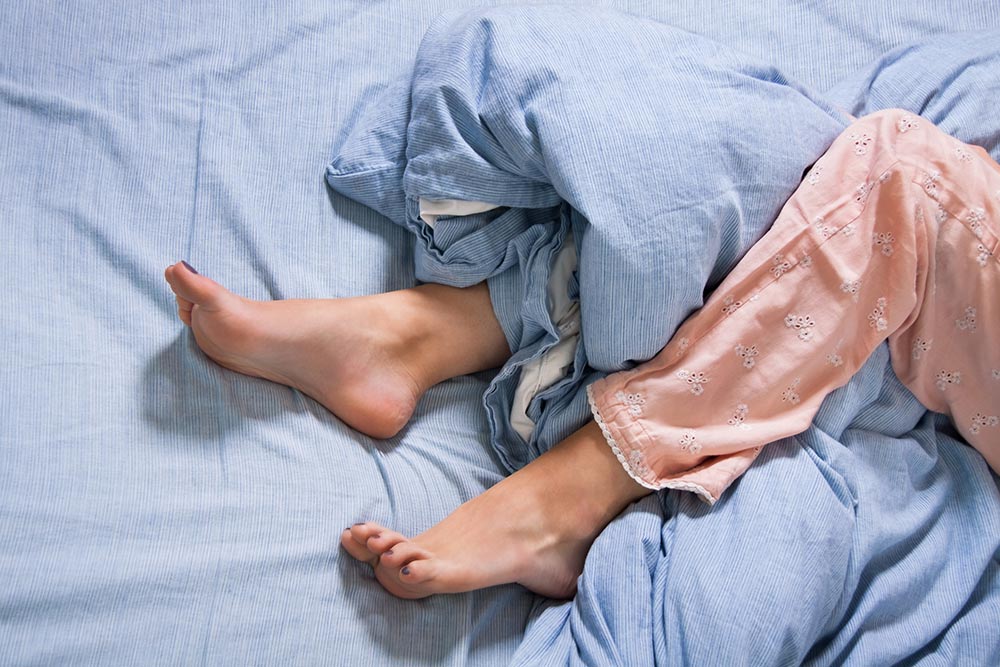 womans legs tangled in a quilt in bed
