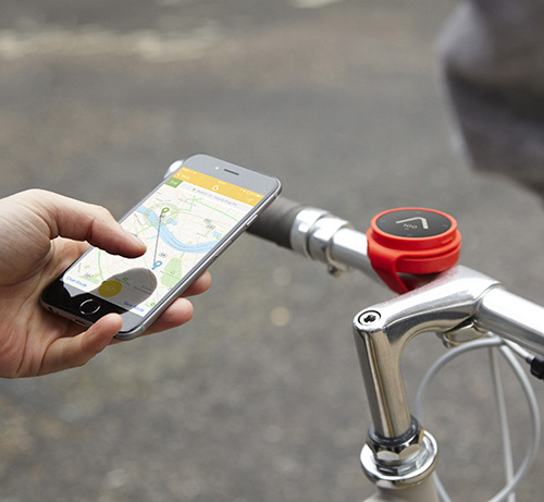 hand holding phone next to a bikes handle bars