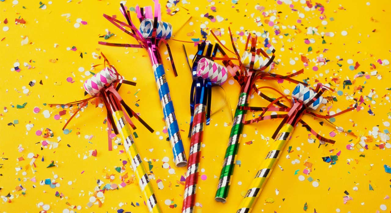 confetti and party blowers on a yellow surface