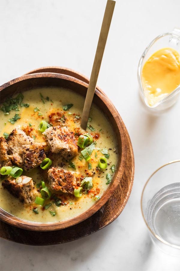 broccoli and cheese soup in a wooden bowl next to a glass of water