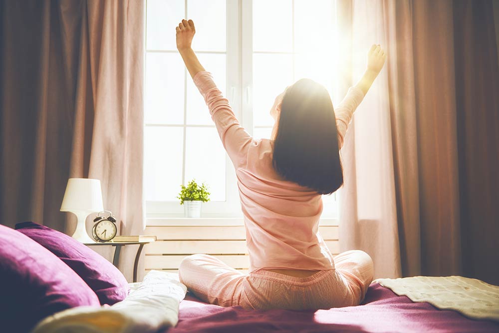 woman stretching on the end of her bed in the morning