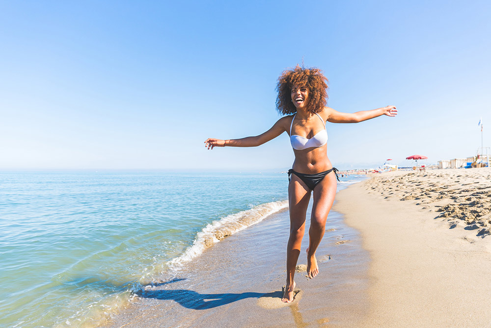 happy woman on the beach in a black and white bikini in the sun