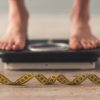 woman standing on scales with a tape measure infront