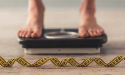 woman standing on scales with a tape measure infront