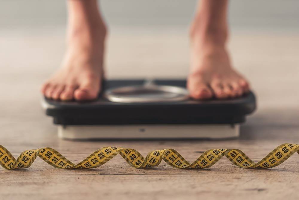 woman standing on scales with a tape measure infront