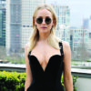 Jennifer Lawrence posing in a black dress and sunglasses on a balcony