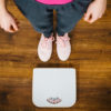 a woman in grey pants and pink tshirt stood next to some scales