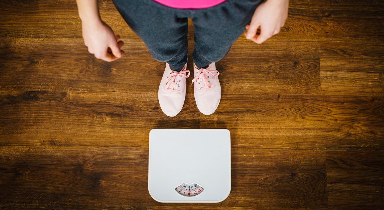 a woman in grey pants and pink tshirt stood next to some scales