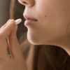 woman holding a vitamin tablet close to her mouth