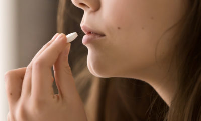 woman holding a vitamin tablet close to her mouth
