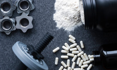 dumbbell weight surrounded by gym supplement powder and pills