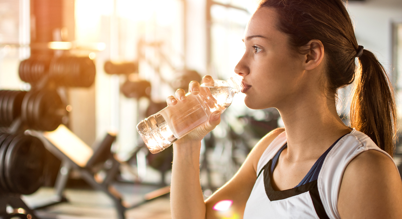 woman sipping water in the gym