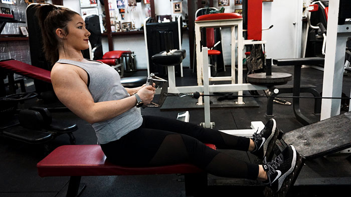 muscular woman in the gym performing a cable row