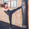 fit woman kicking a punching bag in a workout studio