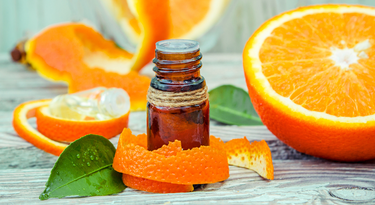sweet orange essential oil bottle surrounded by orange peel and orange