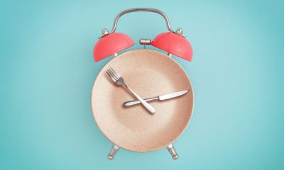 an alarm clock graphic with the face as a plate and the hands as a knife and fork on a light blue background