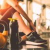 woman sitting down in a gym next to a waterbottle and kettlebell