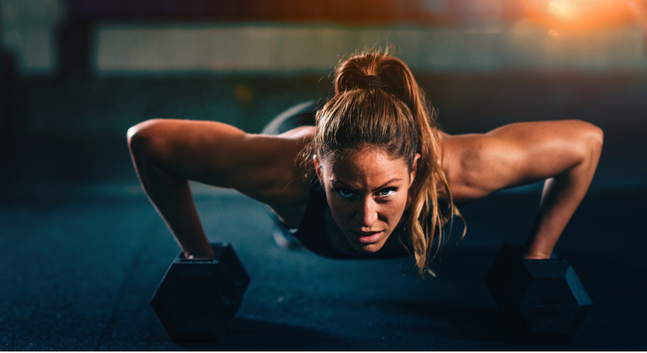 ginger woman performing push ups with dumbbells