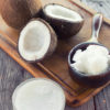 split coconuts on a chopping board and a mini saucepan full of coconut chunks