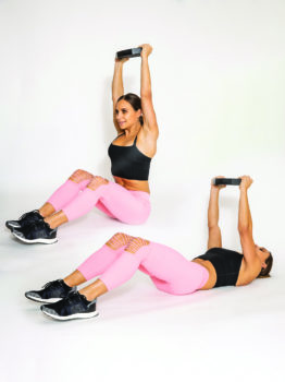 fit woman performing crunch with overhead press