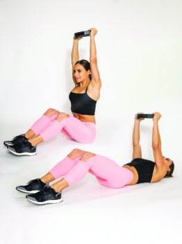 fit woman performing crunch with overhead press