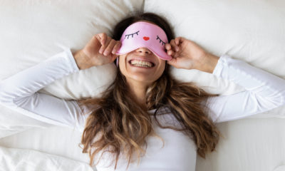 woman in bed smiling with sleep eye mask