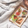 woman lying on bed with breakfast tray