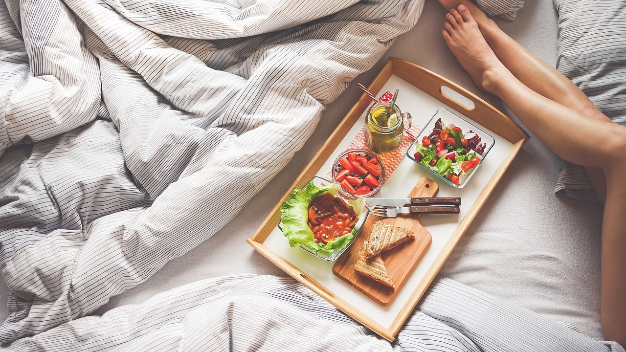 woman lying on bed with breakfast tray