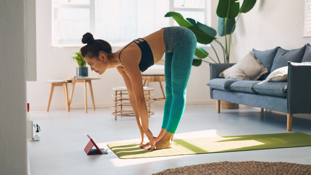 Shot of a young woman using a digital tablet while practicing yoga at home