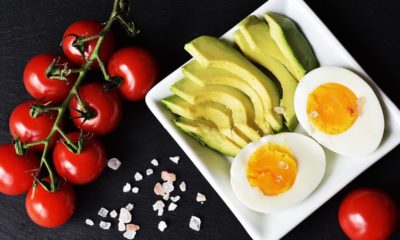 tomatoes on a table next to avocado and eggs on a plate