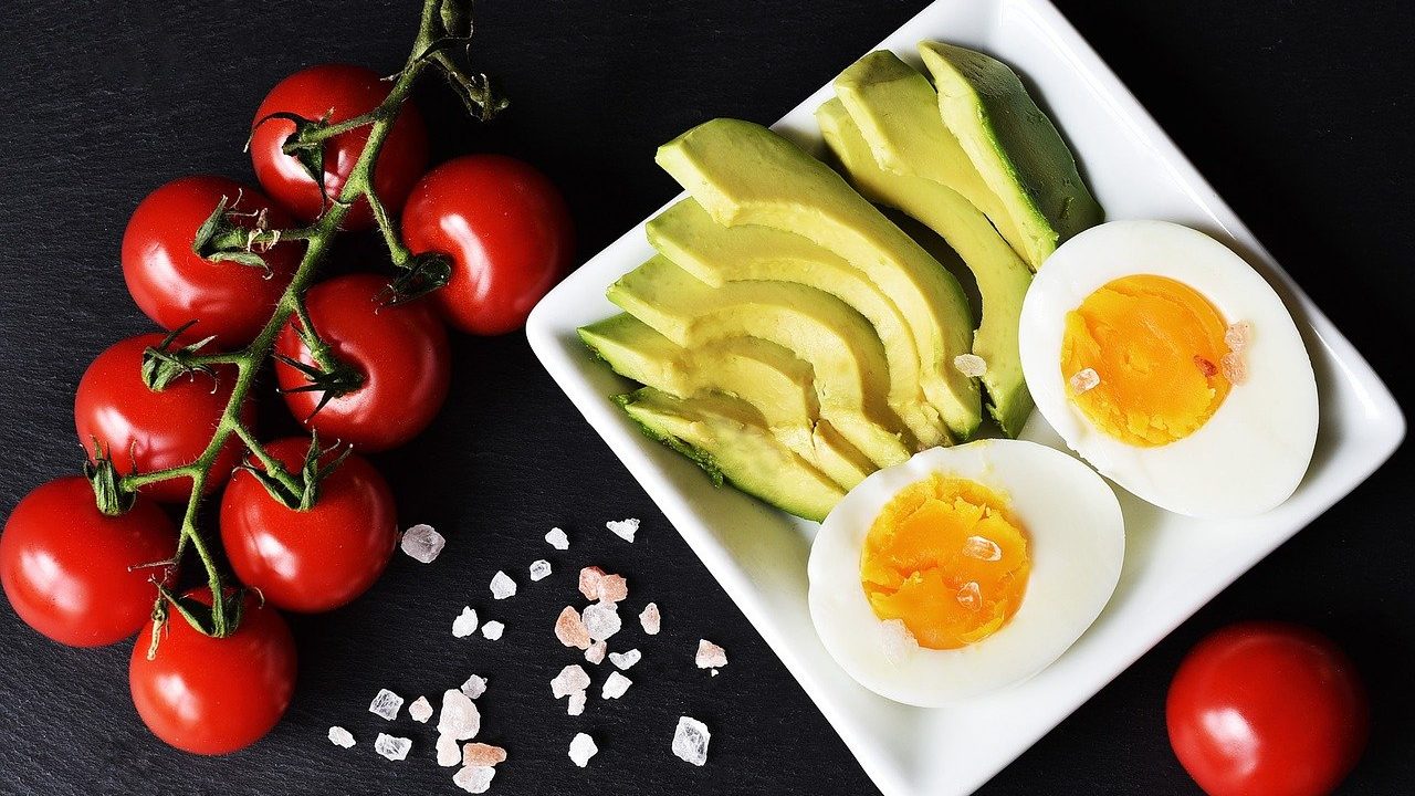 tomatoes on a table next to avocado and eggs on a plate