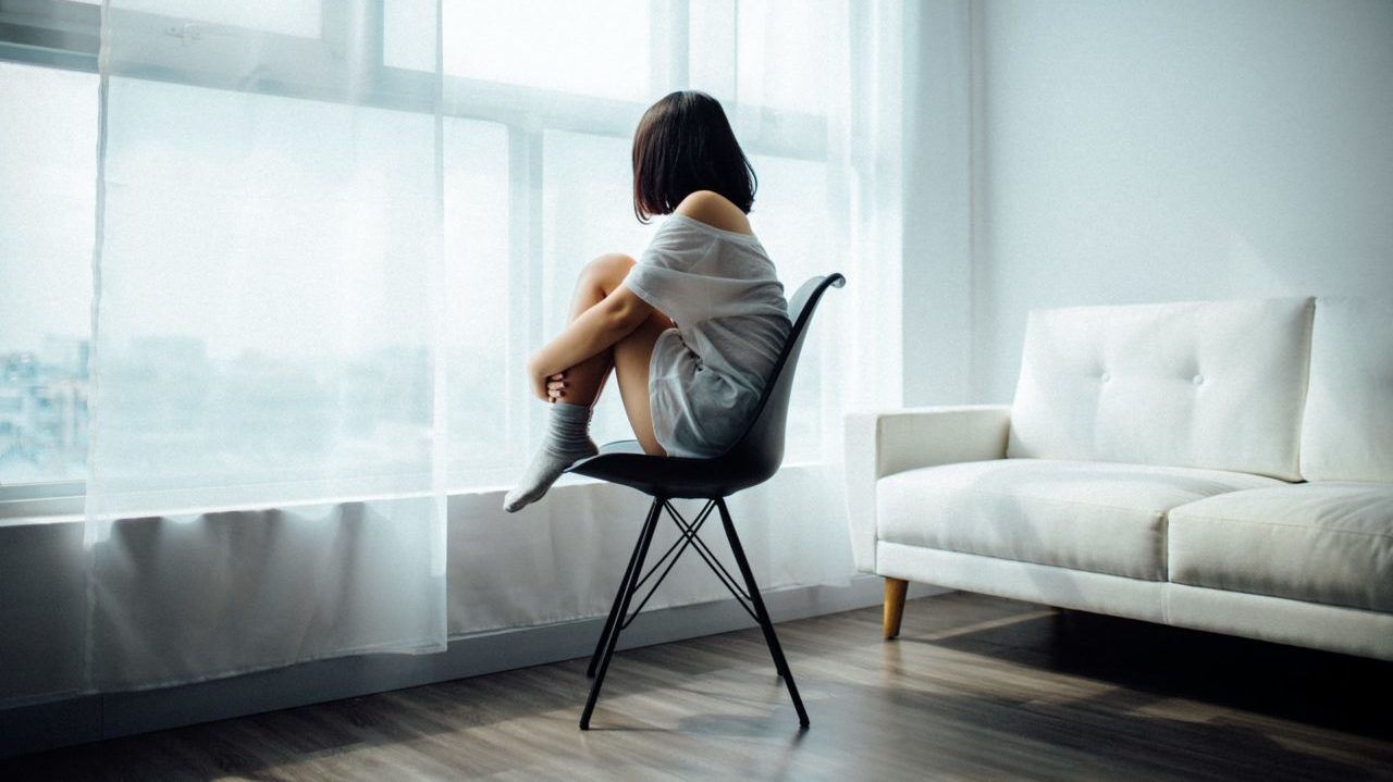 woman sitting on chair staring out the window